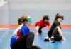 Handling new challenges for children with visual impairment three teenagers sit in a sports hall with their eyes covered