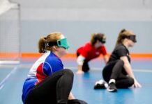 Handling new challenges for children with visual impairment three teenagers sit in a sports hall with their eyes covered
