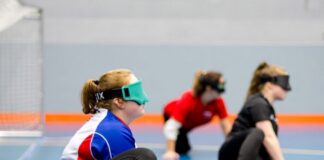 Handling new challenges for children with visual impairment three teenagers sit in a sports hall with their eyes covered