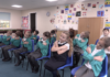 Building secure attachments in the wake of Covid-19 A class of children, all crossing their arms, doing an exercise that promotes good attachment
