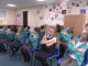 Building secure attachments in the wake of Covid-19 A class of children, all crossing their arms, doing an exercise that promotes good attachment