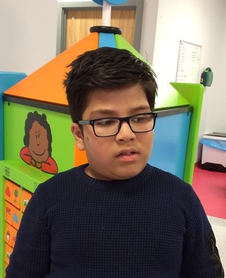 A young boy who has Bardet-Biedl syndrome. He has black hair and is wearing glasses.