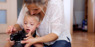 The future of Down’s Syndrome therapy is just around the corner A handicapped down syndrome boy and his mother with a digital camera indoors, taking pictures.
