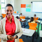 Teacher posing with her tablet at school